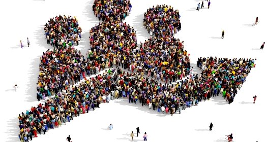 Large and diverse group of people seen from above, gathered together in the shape of a population growth symbol