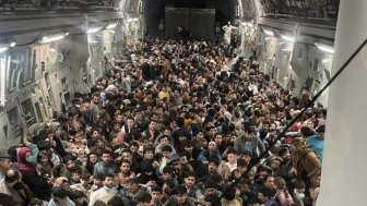 Hundreds of Afghan citizens crowd across the floor of an American military airplane.