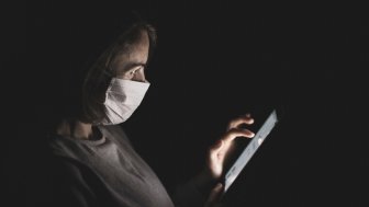 Woman with face mask staring at cell phone