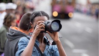 Portland, OR / USA - June 11 2016: Grand floral parade, African American female photographer taking pictures with canon dslr camera.