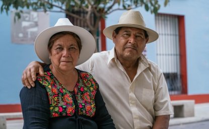 Latin couple of grandparents, sitting outdoors in colorful streets of Oaxaca, Mexico.