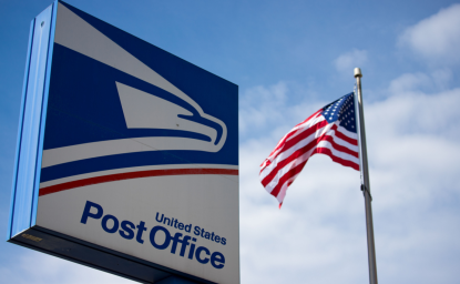 US Post Office Sign With American Flag in the Background