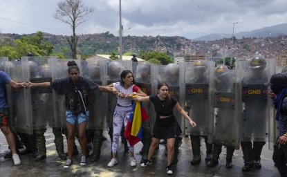 Residents try to block a street to protest the official results the day after the presidential election as National Guards work to remove them in Caracas, Venezuela, Monday, July 29, 2024. (AP Photo/Fernando Vergara)