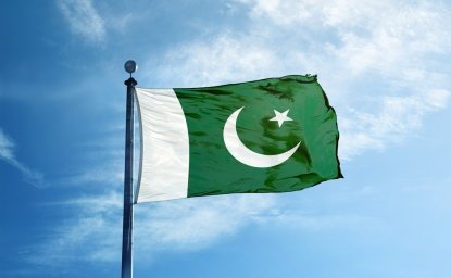 Pakistan flag against blue sky with some white clouds