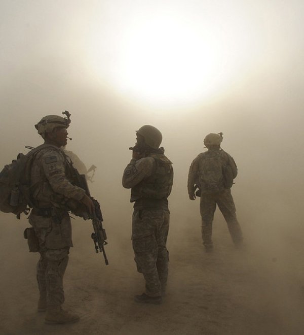 Soldiers watche as CH-47 helicopters circle above during a dust storm at Forward Operating Base Kushamond 