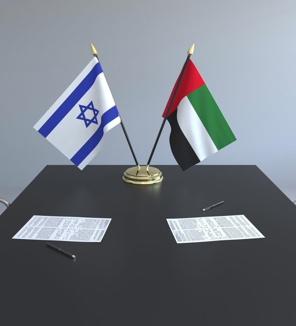 The flags of Israel and the UAE on a conference room table.