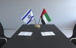 The flags of Israel and the UAE on a conference room table.