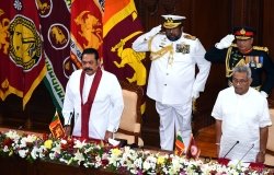 Prime Minister Mahinda Rajapaksa and President Gotabaya Rajapaksa stand in front of two soldiers at a swearing in ceremony