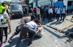  A student helps the police unblock the street during a demonstration in Haiti, Port-au-Prince
