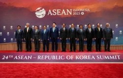 A group of ASEAN leaders stand in front of the logo for the 2023 ASEAN Summit.