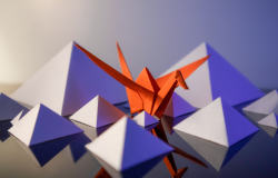 Abstract origami pyramids and a crane sit on a reflective surface.